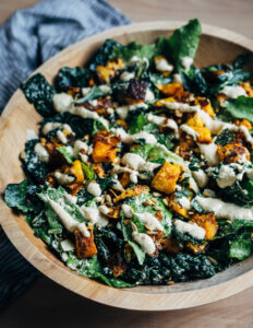 A wooden bowl with a kale salad.