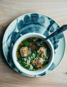 A bowl of Italian wedding soup on a decorative plate.