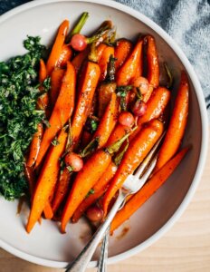 A bowl of glazed carrots with a green chimichurri alongside.