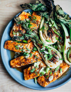 A platter with saucy bok choy halves and salmon fillets.