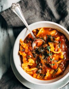 A bowl of pasta soup with winter vegetables.
