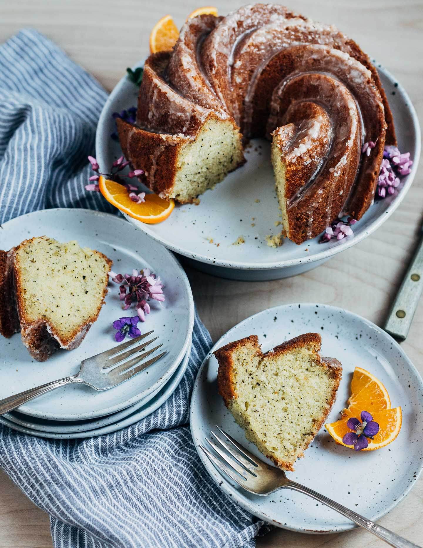 A bundt cake on a cake stand with slices on plates all around it.