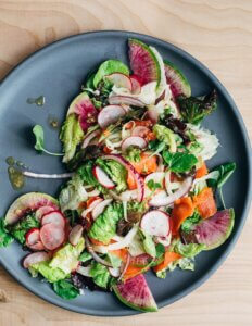 A platter with smoked salmon, lettuce, and radishes.