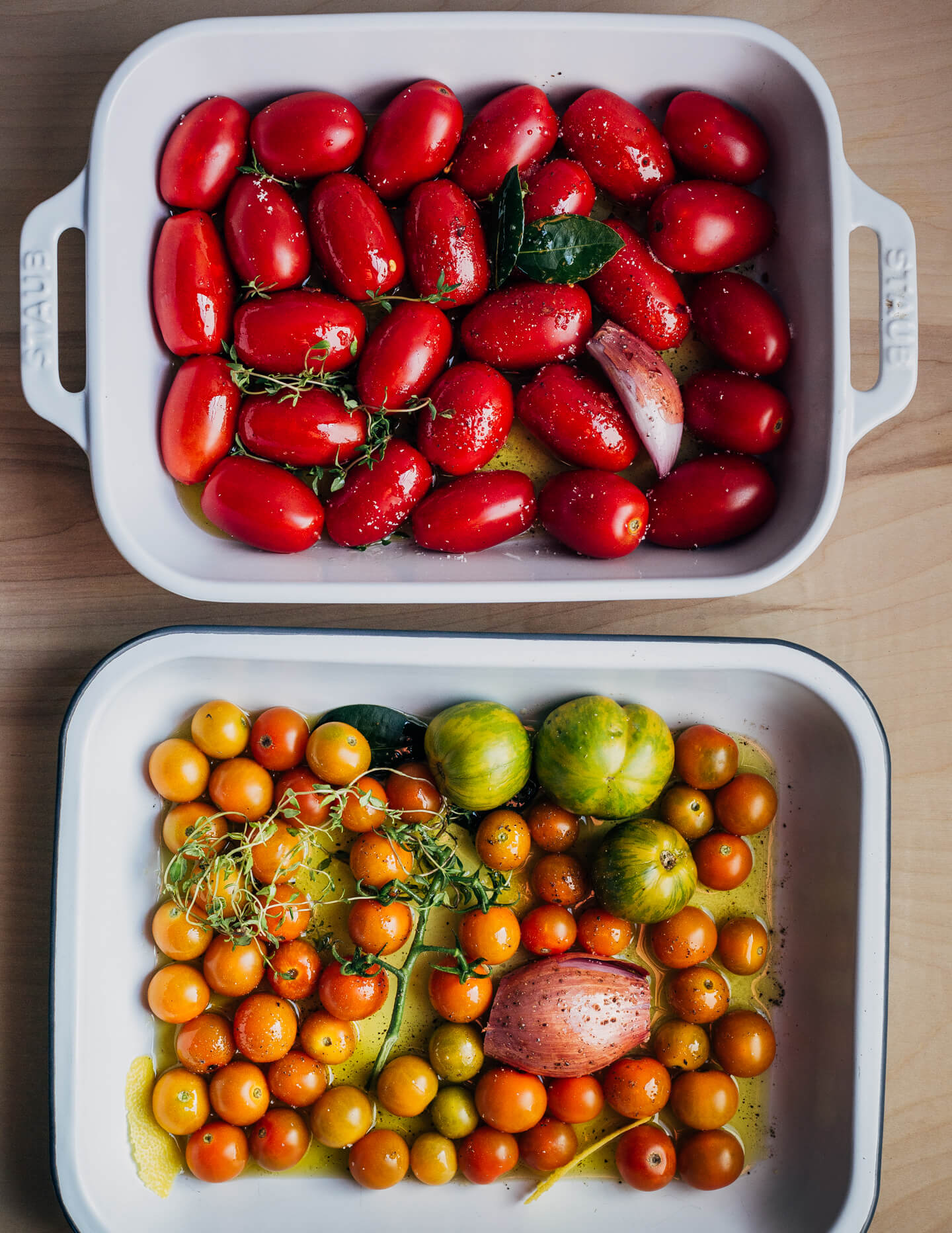 Two baking dishes filled with all the ingredients for tomato confit