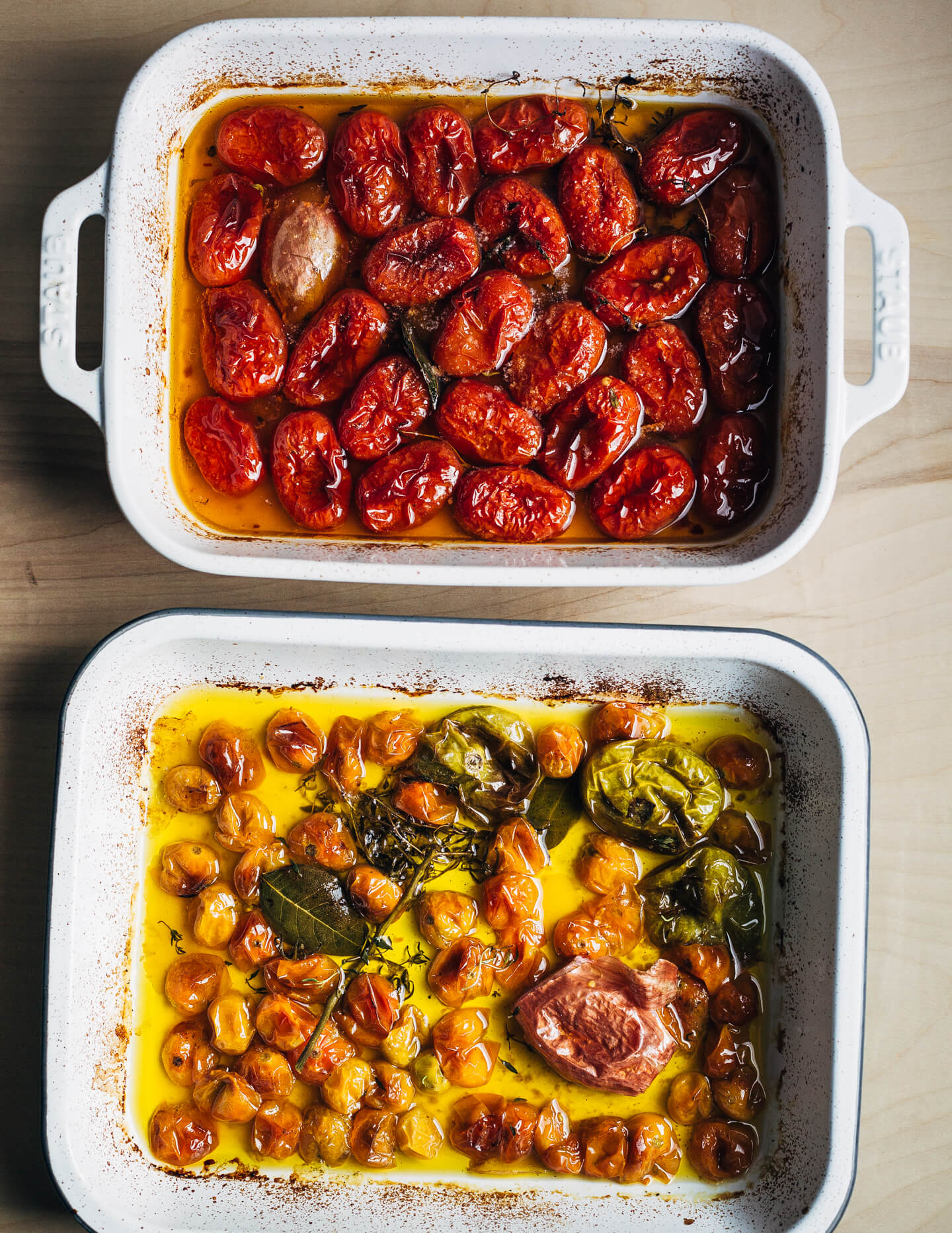 Two baking dishes with cooked tomato confit, one with red tomatoes and one with yellow. 