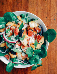 A serving bowl with a cantaloupe, fig, and watercress salad.