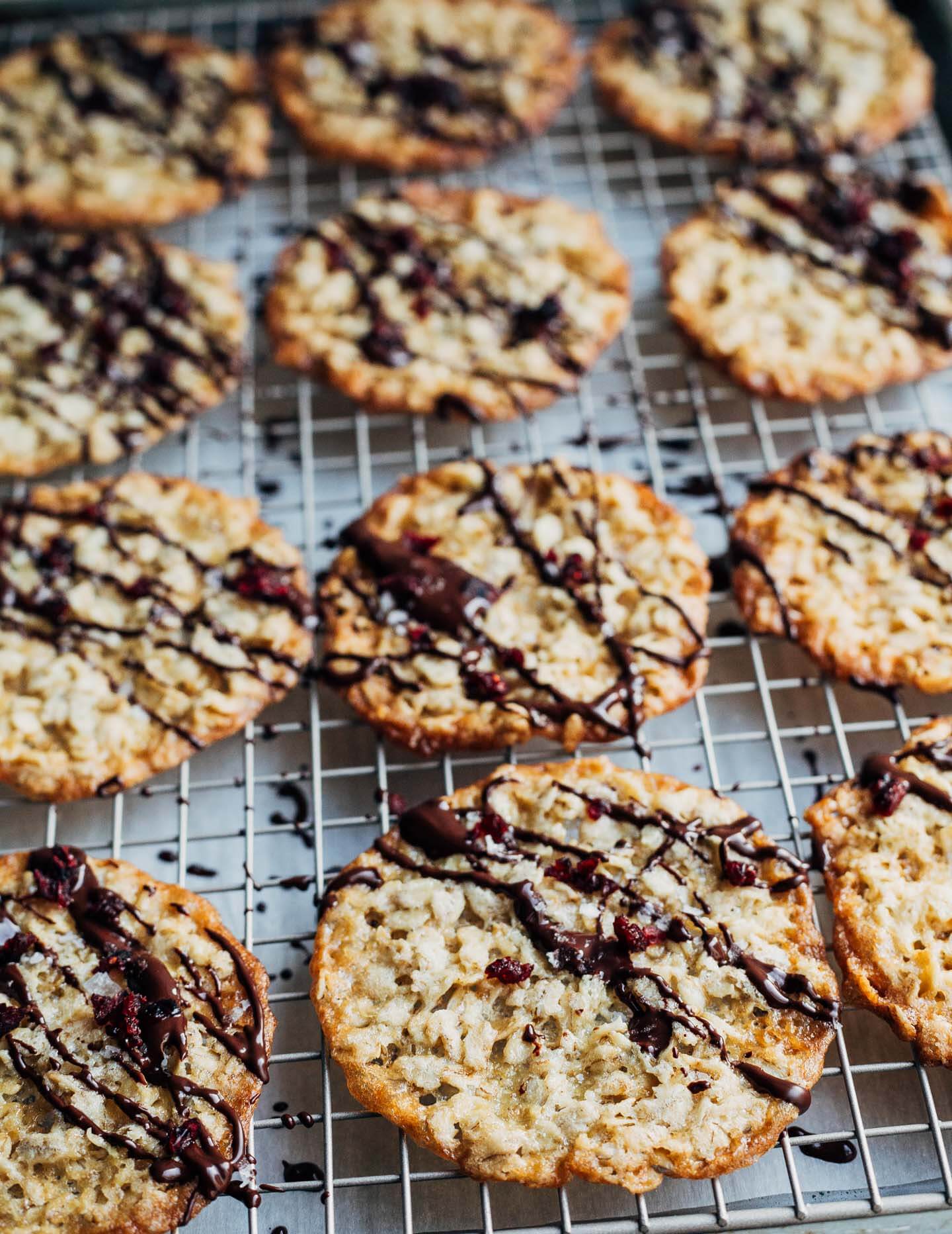 Chocolate-drizzled oatmeal cookies on a baking rack.