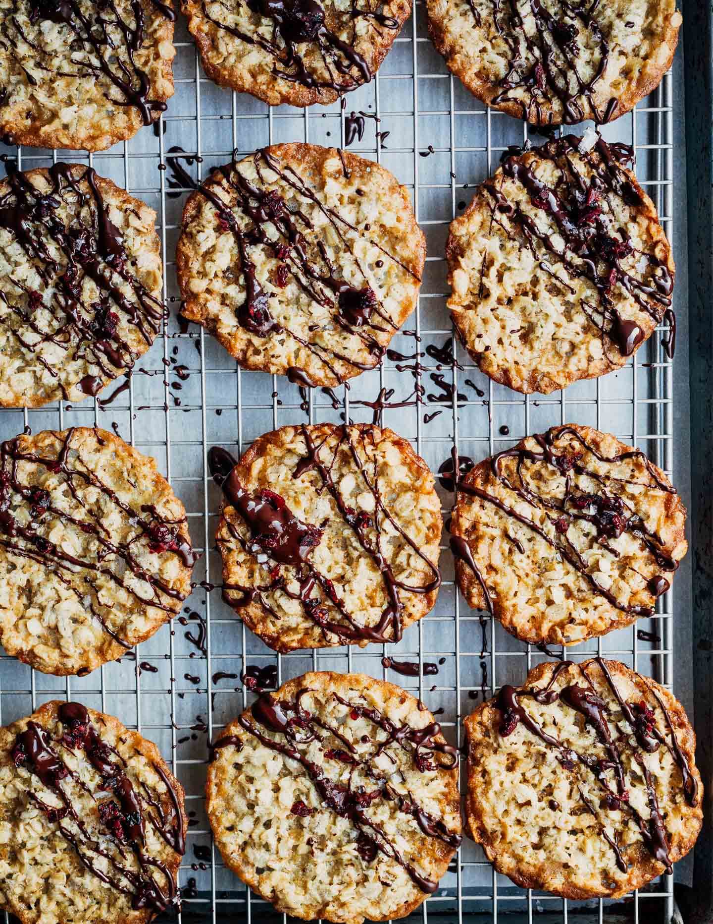 Chocolate-drizzled oatmeal cookies on a baking rack. 