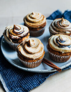 A plate with frosted, molasses-swirled pumpkin cupckaes.