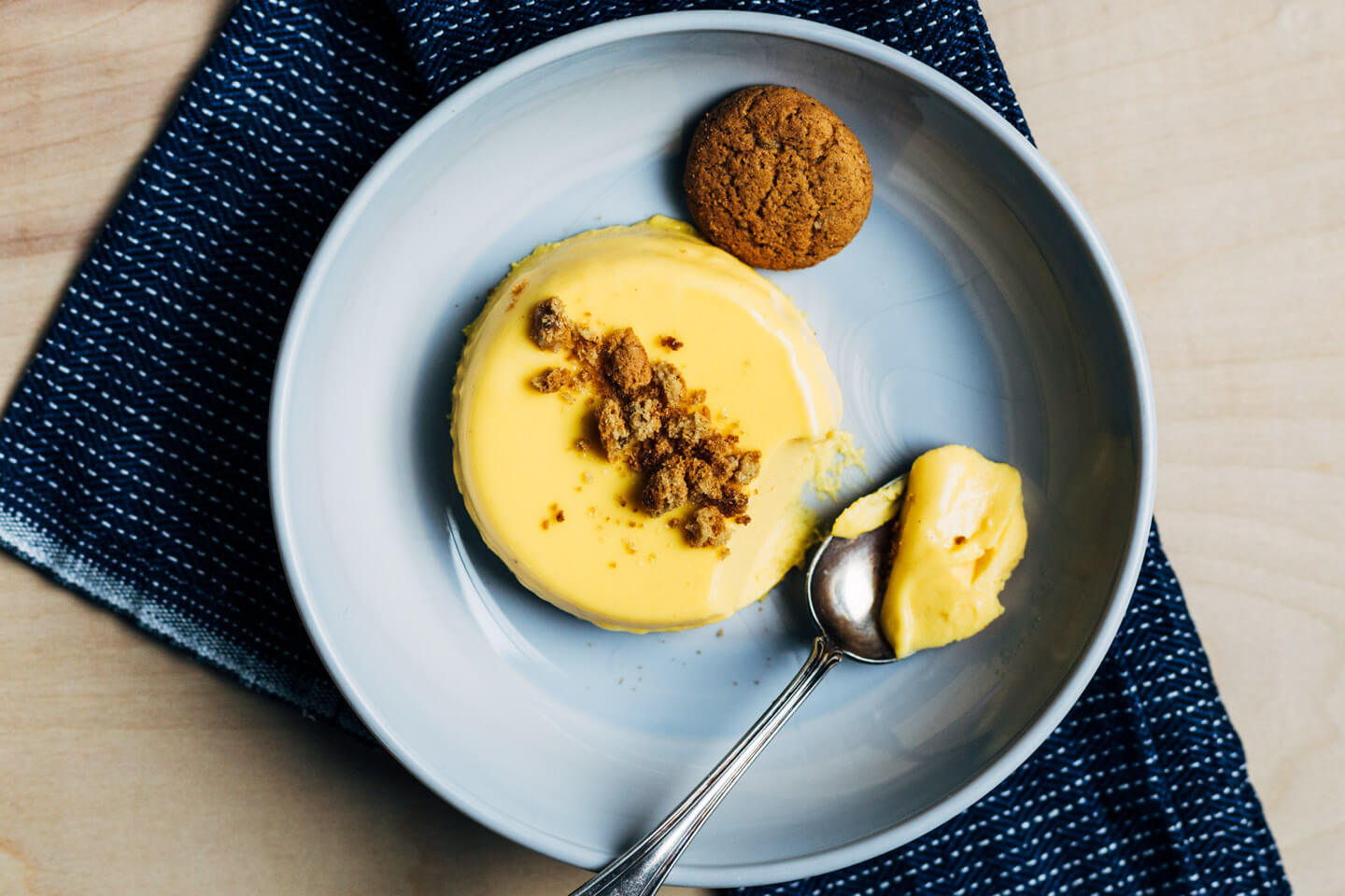 A serving dish with pumpkin panna cotta, there’s a spoon alongside with a bite of custard. 