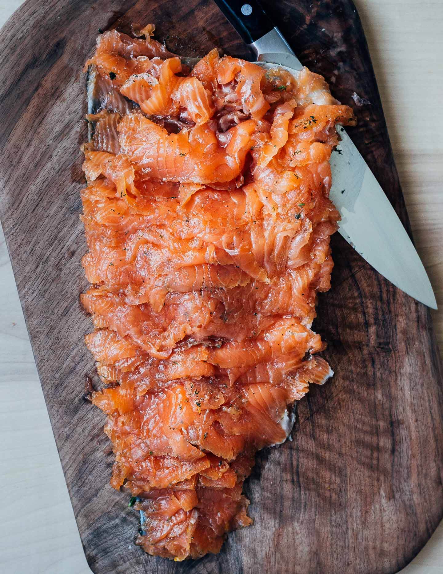 Sliced gravlax on a cutting board with a knife alongside. 