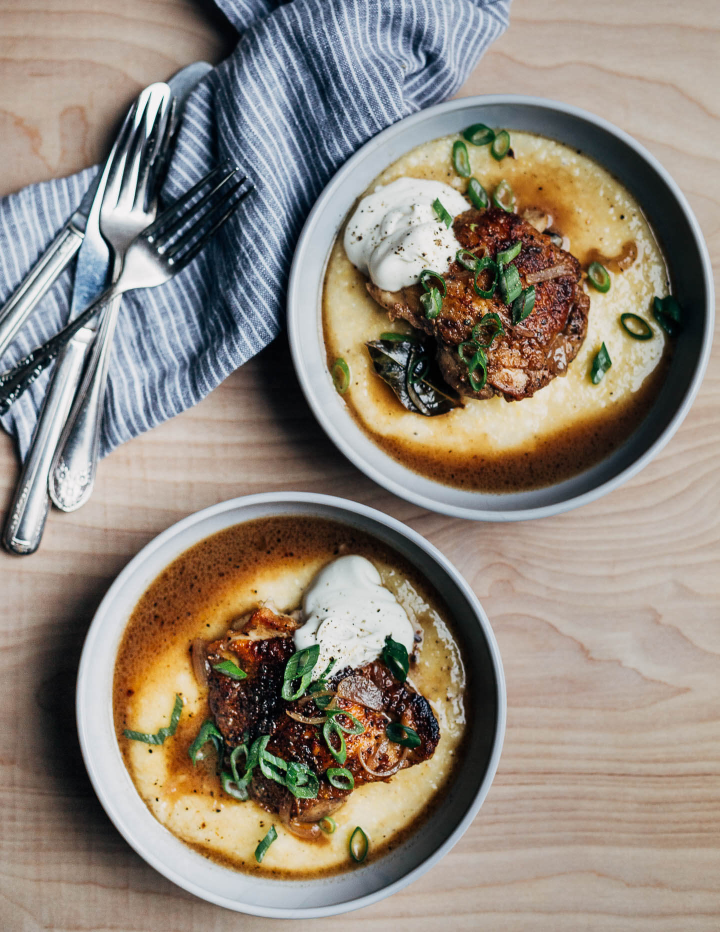 Two bowls of vinegar chicken with polenta, green onions, and creme fraiche.