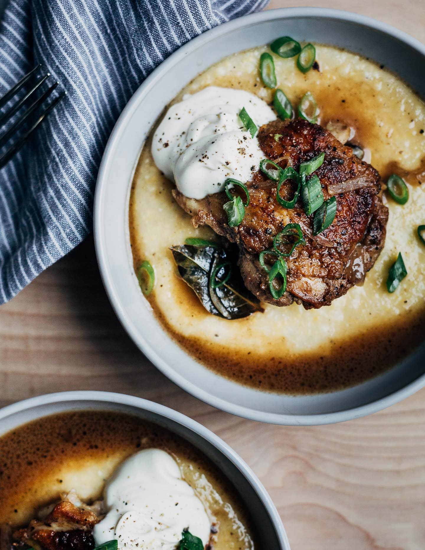 Two bowls of vinegar chicken with polenta, green onions, and creme fraiche. 