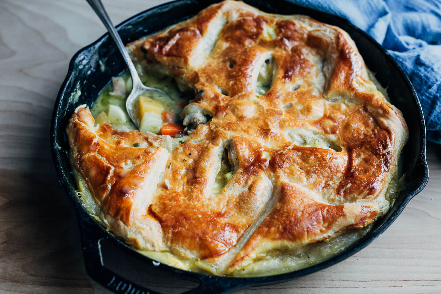 A skillet of chicken pot pie with a spoon getting a serving. 