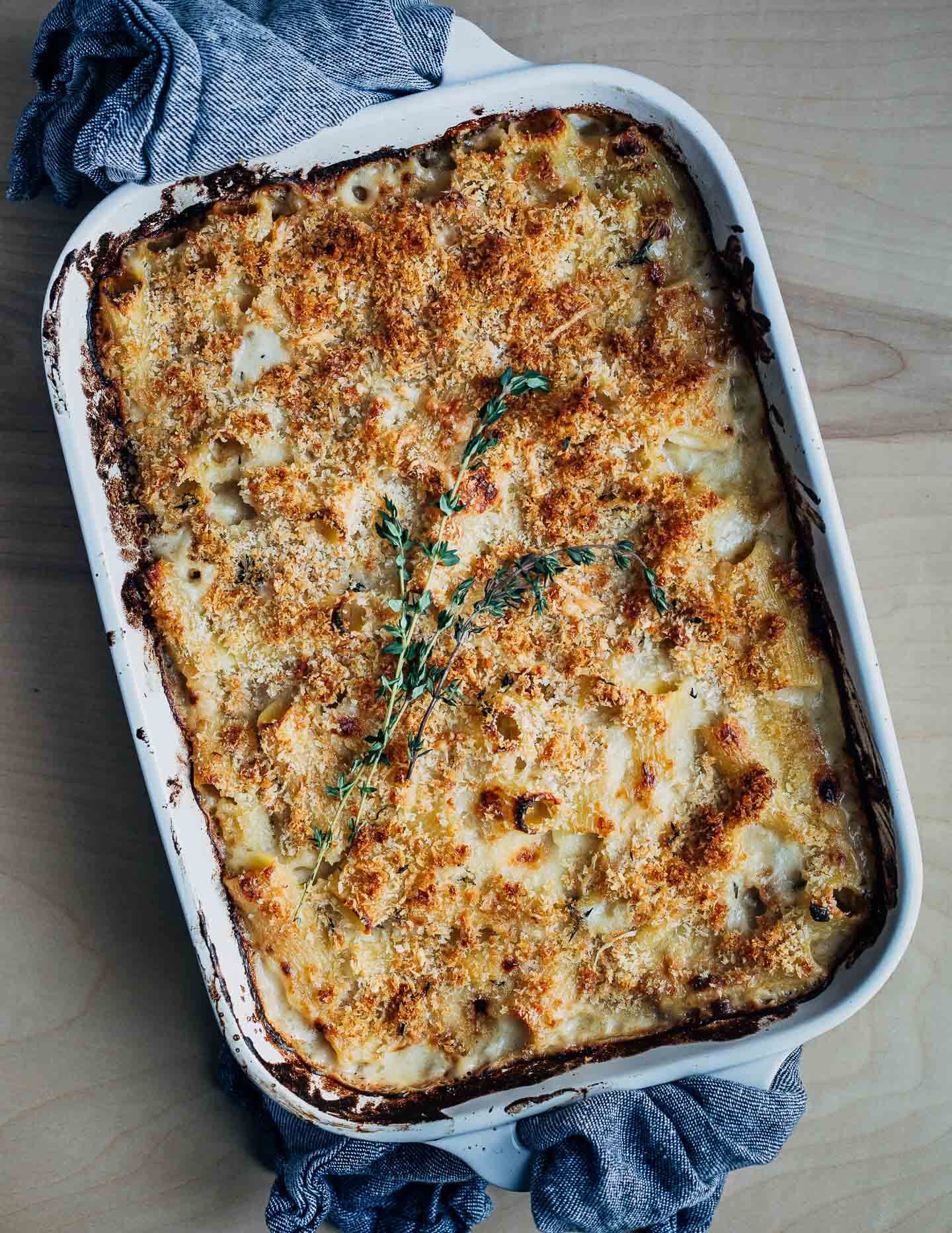 Baked mac and cheese in a baking dish, with blue towels on the handles. 